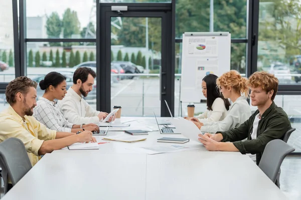 stock image multiethnic business people working with gadgets and documents at conference table in office