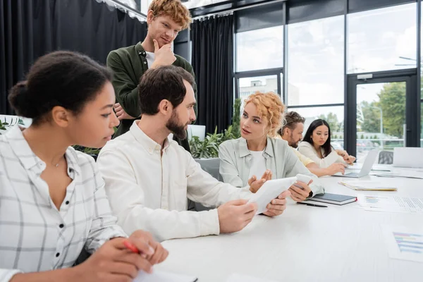 Thoughtful Redhead Man Looking Colleagues Talking Multiethnic Team Meeting Room — Stock Photo, Image