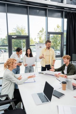 Multiethnic business people working with papers during meeting in office  clipart