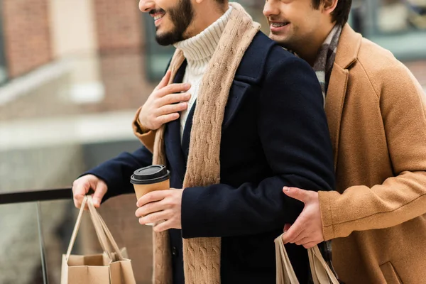 笑顔のゲイ男抱擁ひげを生やしたボーイフレンドとともにコーヒーを飲みに行くと買い物袋 — ストック写真