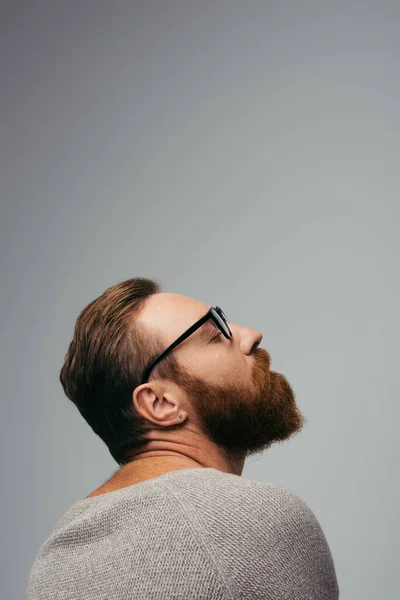 stock image Side view of trendy bearded man in eyeglasses closing eye isolated on grey 
