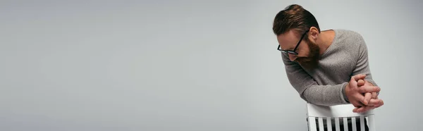 Модний Чоловік Окулярах Дивиться Вниз Біля Стільця Ізольовано Сірому Банер — стокове фото