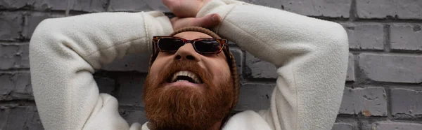 Счастливый Бородатый Мужчина Шапочке Модных Солнцезащитных Очках Смеется Возле Кирпичной — стоковое фото