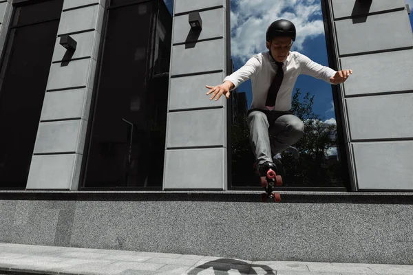 戴着钢盔和溜冰鞋在城市街道上跳跃的商人 — 图库照片
