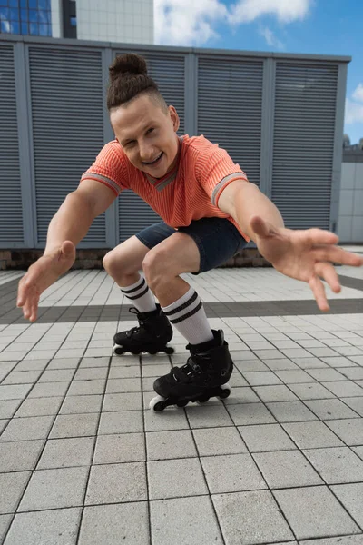 ポジティブなローラースケートは手を伸ばし 都市部の通りにカメラでウィンク — ストック写真
