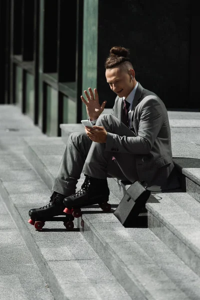 Leende Rullskridskoåkare Kostym Viftar Hand Videosamtal Smartphone Medan Sitter Urban — Stockfoto