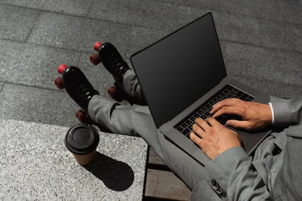 穿着旱冰鞋的裁缝店老板的头像 他在笔记本电脑上打字 咖啡旁边的屏幕空白 然后到户外去 — 图库照片