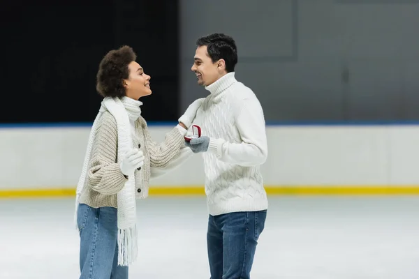 从侧面看非洲裔美国女人抱着男朋友 在冰球场上戴着求婚戒指 — 图库照片
