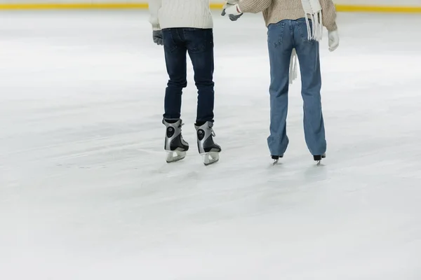 カップル保持手とスケートリンク上のアイススケートの作物ビュー — ストック写真