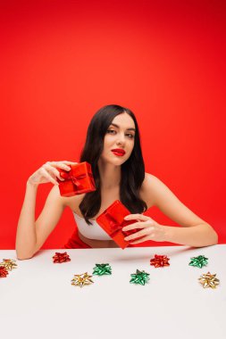 Yüzü olan güzel bir model hediye yanında sunar kırmızıda izole edilmiş yaylar 