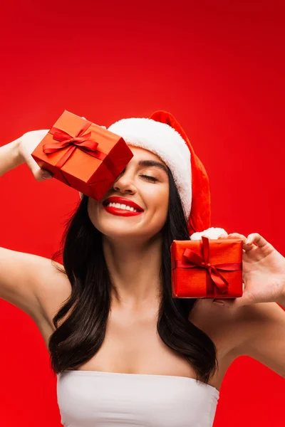Усміхнена Жінка Зверху Санта Капелюх Посміхається Тримає Подарунки Ізольовані Червоному — стокове фото