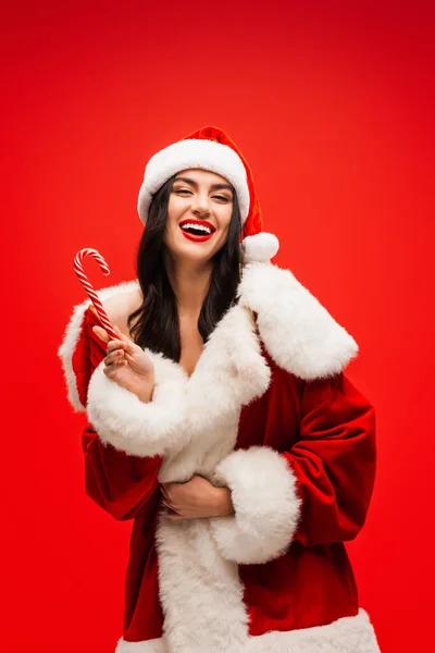 Fröhliches Junges Model Weihnachtsmannkostüm Mit Gestreiftem Lutscher Auf Rotem Grund — Stockfoto