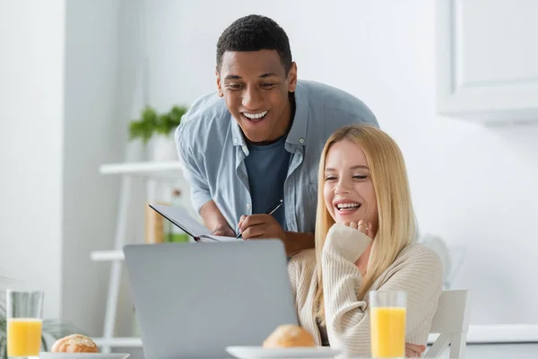 Fröhliche Frau Blickt Auf Laptop Neben Afrikanisch Amerikanischem Freund Mit — Stockfoto