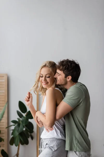 Homem Alegre Abraçando Namorada Positiva Pijama Casa — Fotografia de Stock