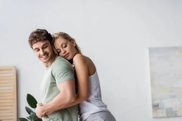 Pijamalı Sarışın Kadın Evde Gülümseyen Erkek Arkadaşı Kucaklıyor — Stok fotoğraf