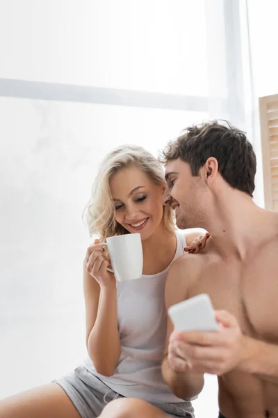 Sexy Mann Hält Verschwommenes Smartphone Neben Freundin Mit Tasse Kaffee — Stockfoto