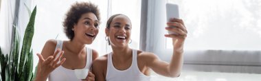 Mutlu Afro-Amerikan lezbiyen kadın kız arkadaşıyla selfie çekiyor elinde kahve, afiş