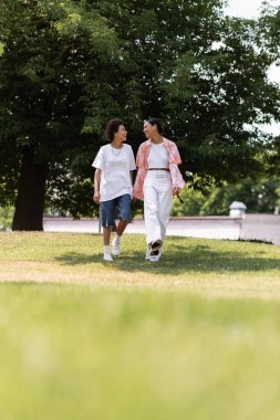 Tam boy Afro-Amerikan kadın el ele tutuşuyor ve Green Park 'ta lezbiyen partnerle yürüyor. 