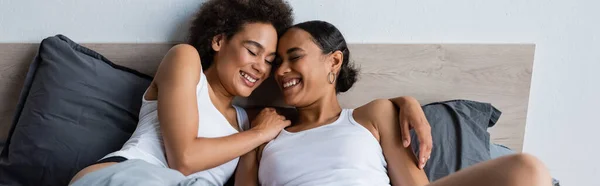 幸福而又同性恋的非洲裔美国夫妇 紧闭双眼躺在床上 高举横幅 — 图库照片