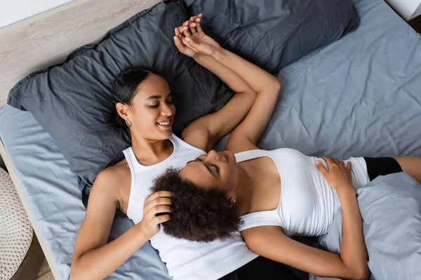 非洲卷曲女同性恋者的头像美国女人和快乐的女朋友躺在床上 — 图库照片