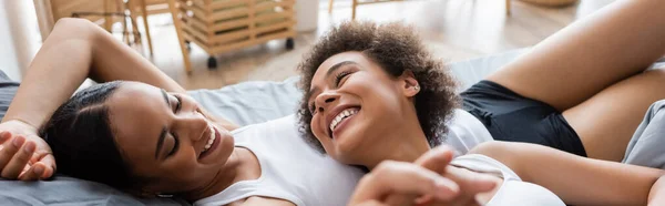 非洲女同性恋者手牵着手 与快乐的女友躺在床上 高举横幅 — 图库照片
