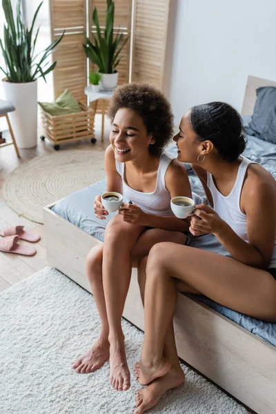 快乐的非洲女同性恋 非洲裔美国夫妇坐在床上 一边喝着咖啡 — 图库照片