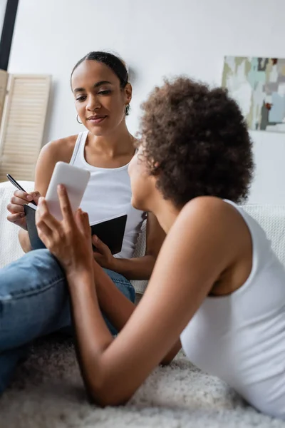 Krullend Afrikaans Amerikaanse Vrouw Tonen Smartphone Naar Vriendin — Stockfoto