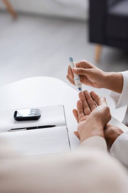 cropped view of african american doctor taking blood sample of patient with diabetes in clinic  clipart