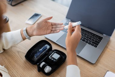 Cropped view of african american businesswoman using lancet pen near devices in office  clipart