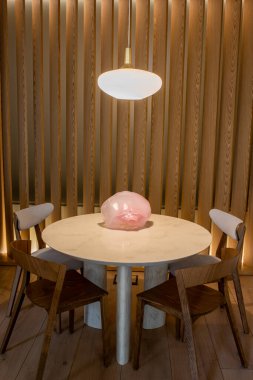 pink decorative figurine on round dining table near wooden chairs 