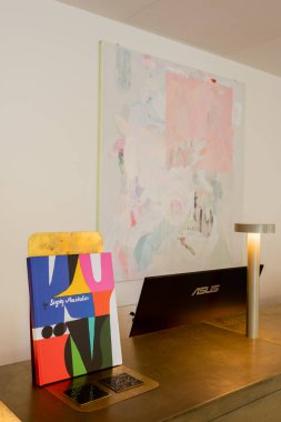 abstract painting on wall near reception desk with art book and computer monitor 