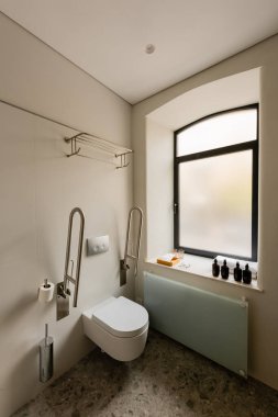 interior of white bathroom with toilet for disabled people in hotel 