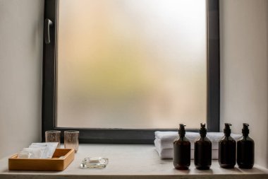 bottles with bathroom accessories near fresh towels in hotel 