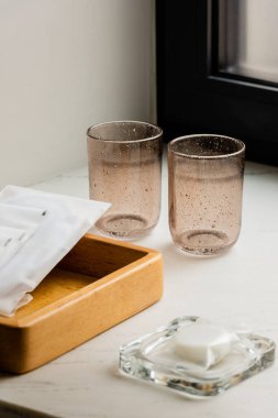 clean glasses near wooden tray with sachets with wet wipes and soap 