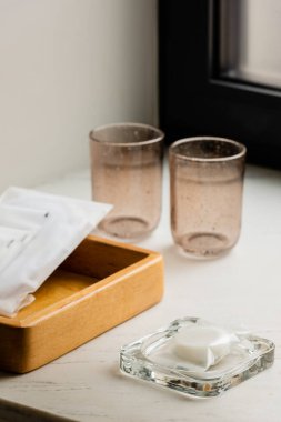 glasses near wooden tray with sachets with wet wipes and soap 