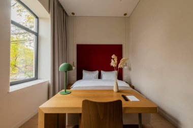 wooden desk and chair near comfortable bed in hotel room 