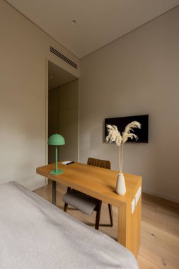wooden desk and chair near tv flat screen on wall in hotel room  clipart