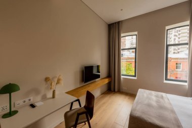 wooden chair near workspace and flat tv screen on wall in bedroom of hotel 