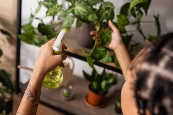 stock image partial view of tattooed african american florist holding spray bottle near blurred plants in flower shop