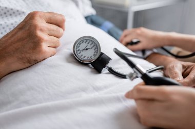 Tonometresi olan bir doktorun hastane yatağında kan basıncını ölçtüğü görüntüler. 