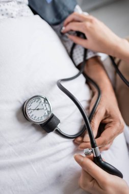 Hastanedeki hasta yatağında tonometre kullanan doktorun üst görüntüsü. 