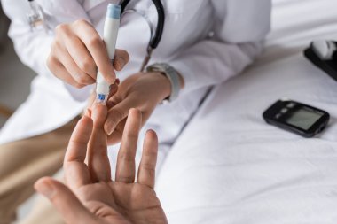 Kalemli bir doktorun klinikteki hastanın kan şekerini ölçtüğü görüntüler. 