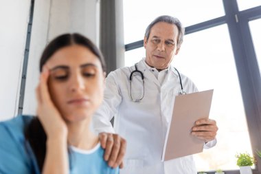 Hastane koğuşunda, kağıt klasörü olan kıdemli doktor bulanık hastayı sakinleştirdi 