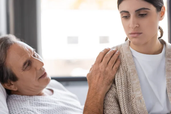 Stock image Blurred senior patient calming upset daughter in hospital ward 