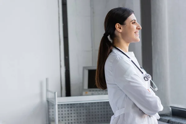 Side view of positive doctor in white coat standing in clinic