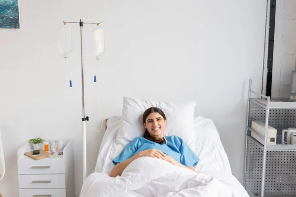 Stock image Cheerful patient looking at camera near intravenous therapy in clinic 