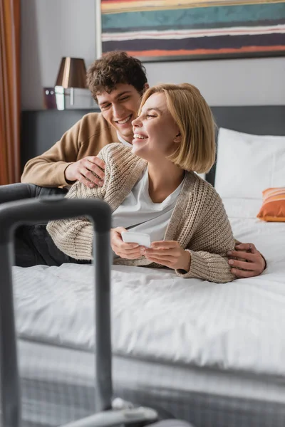 Joyful Woman Holding Mobile Phone Smiling Boyfriend Hotel Bedroom Blurred — Stockfoto
