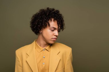 Sarı gömlekli ve ceketli kıvırcık saçlı Afro-Amerikan bir adam.