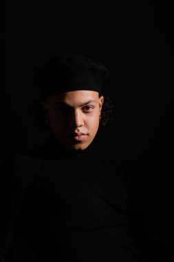 Siyah üzerine izole edilmiş şık bereler takan siyah yüzlü Afrikalı Amerikalı genç bir adamın portresi.