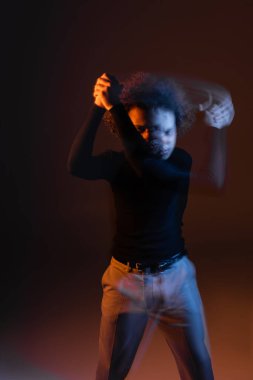 Uzun süre yaralı Afro-Amerikan bir adamın karanlık arka planda, turuncu ve mavi ışıklı bipolar bozukluğu vardı.